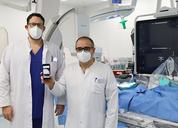 Zwei Ärzte im Krankenzimmer halten ein Handy hoch