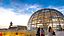 Die Bundestagsglaskuppel in den Wolken von Berlin, davor gehen Menschen