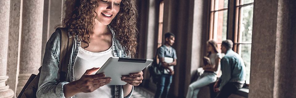 Studierende schaut lächelnd auf ein Tablet