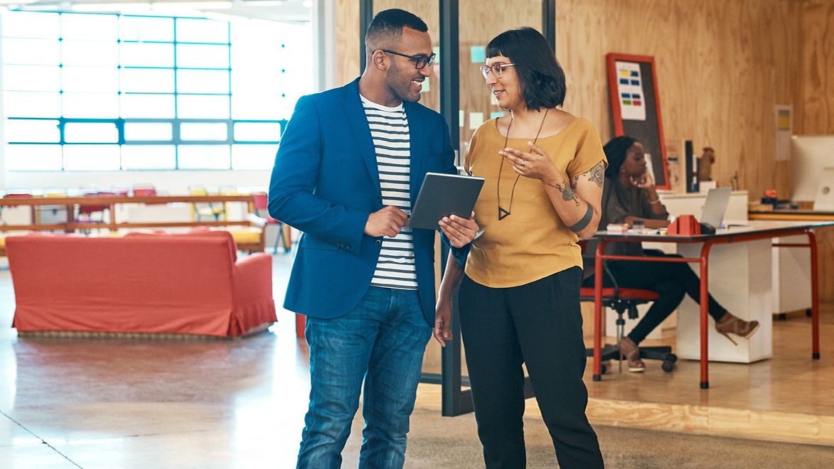 Zwei Personen stehen im Büro und unterhalten sich