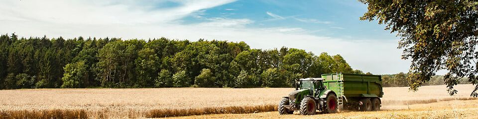 Ein Traktor mit Anhänger fährt auf einem Strohfeld im Landkreis Diepholz