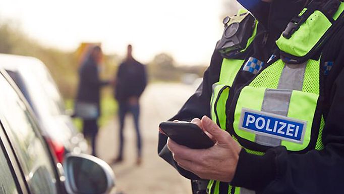 Polizistin der Landespolizei Brandenburg hält Smartphone in der Hand