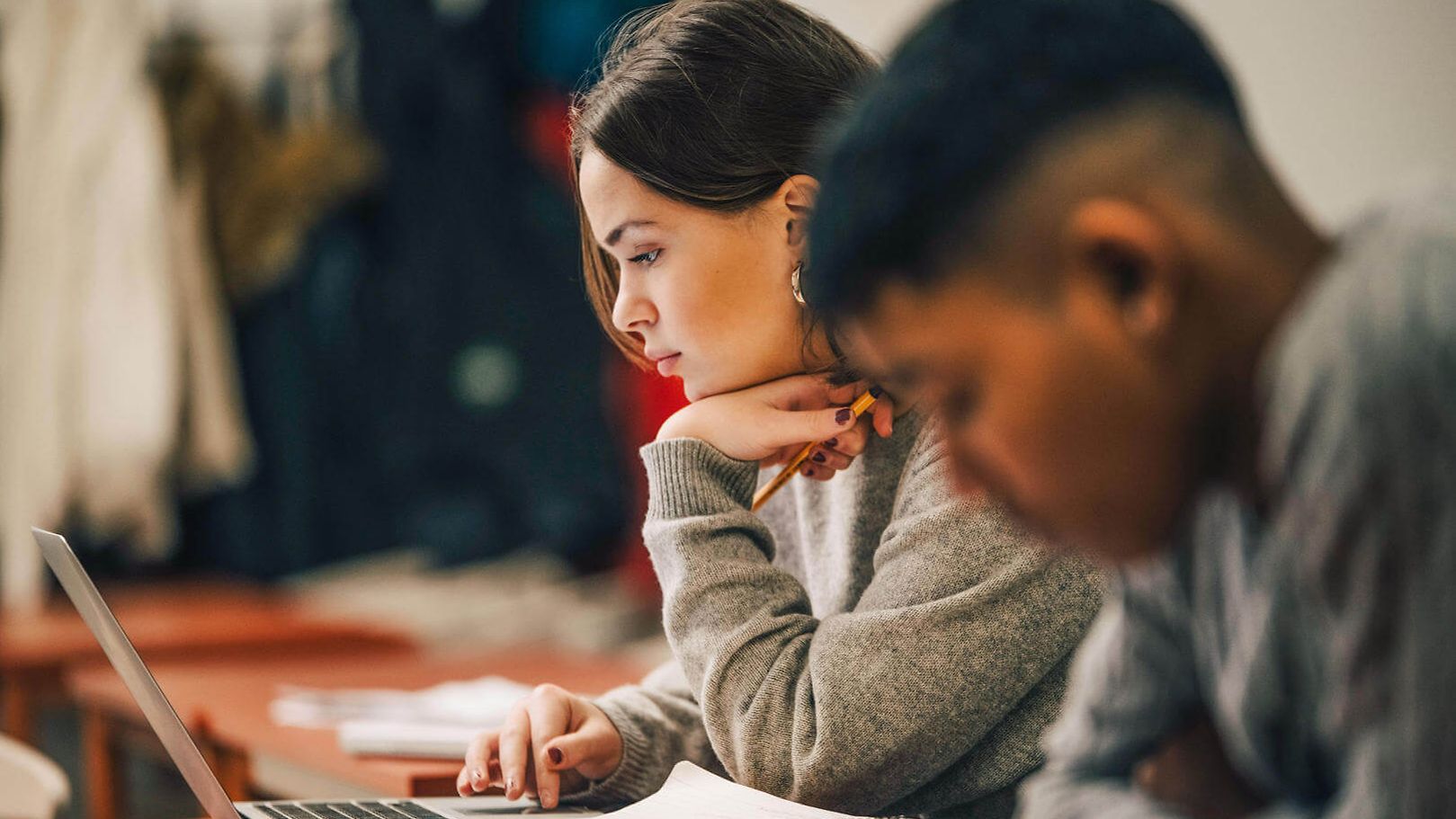 Lachende Kinder in Klassenzimmer über Laptops gebeugt