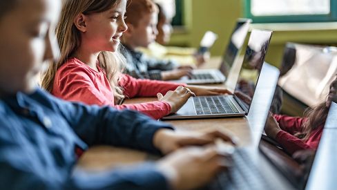 Mehrere Kinder sitzen an Laptops