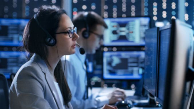 IT-Fachkräfte in einem Kontrollzentrum mit Headsets vor Monitoren und Datenvisualisierungen