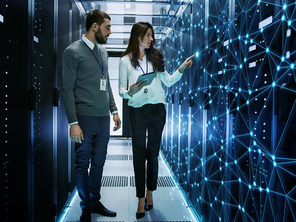 Personen in einem Serverraum mit digitaler Netzwerkvisualisierung
