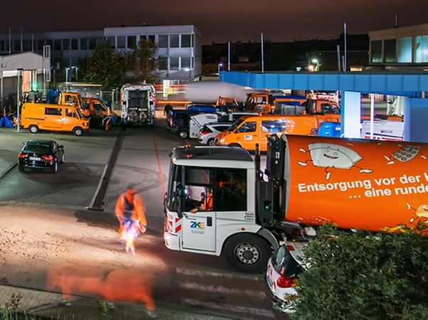 Fahrzeuge und Mitarbeitende des kommunalen Entsorgungsbetriebs Saarbrücken auf einem Betriebshof bei Nacht.