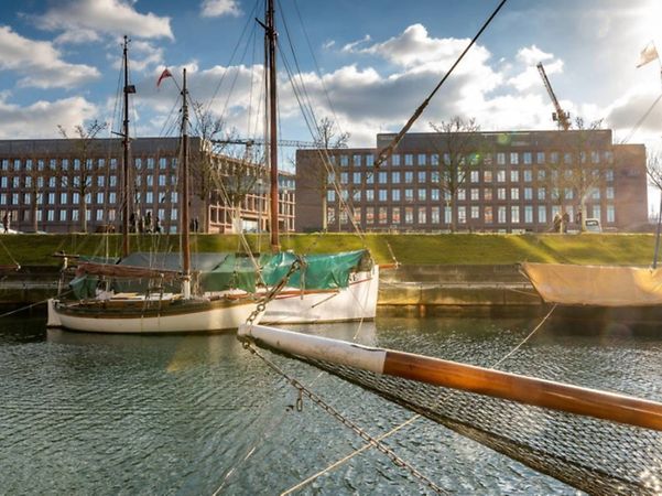 Gebäude der Investitionsbank Schleswig-Holstein am Wasser mit Segelbooten im Vordergrund.