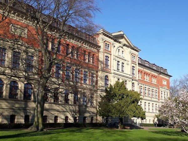 Historisches Hochschulgebäude der Hochschule Anhalt mit großer Grünfläche und Bäumen davor.