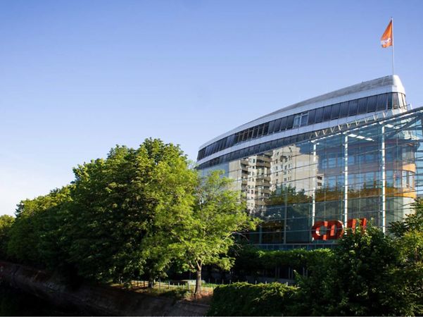 Bürogebäude der CDU mit Glasfassade, umgeben von Bäumen und einem Kanal.
