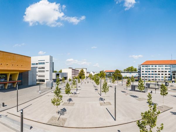 Campus der Technischen Universität Chemnitz mit modernem Platz, Bäumen und Hochschulgebäuden.
