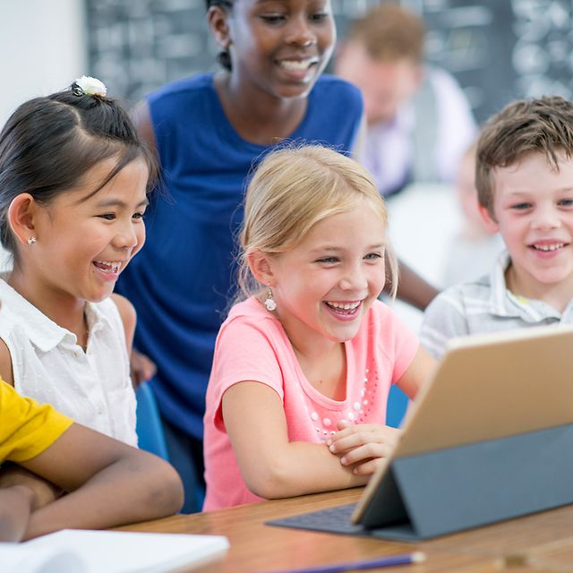 Grundschulkinder lernen gemeinsam mit einem Tablet im Klassenzimmer