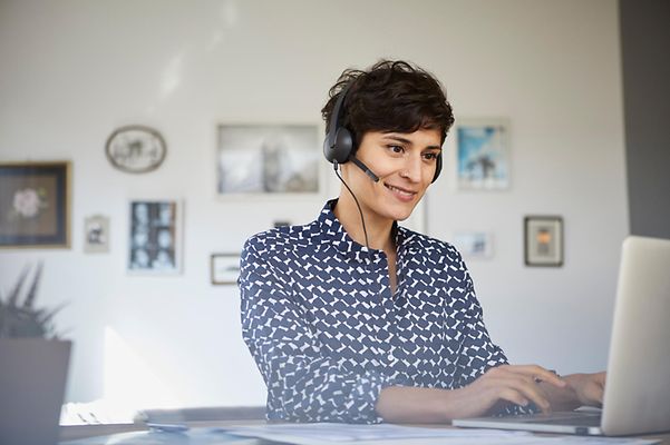 Telekom-Mitarbeiterin berät Kundin oder Kunde via Telefonat am Computer.