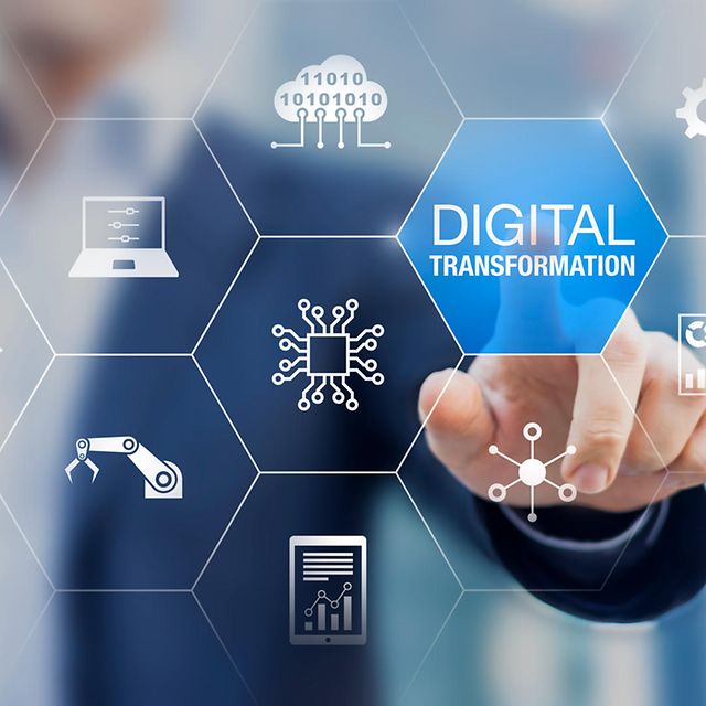 A man in a suit blurred in the background points his finger at a grid with the words 'Digital Transformation' written on it.