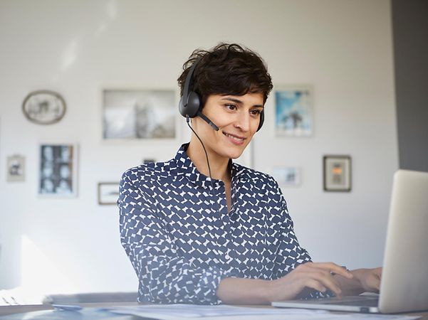 A Telekom employee advises a customer over the phone whilst working at a computer.