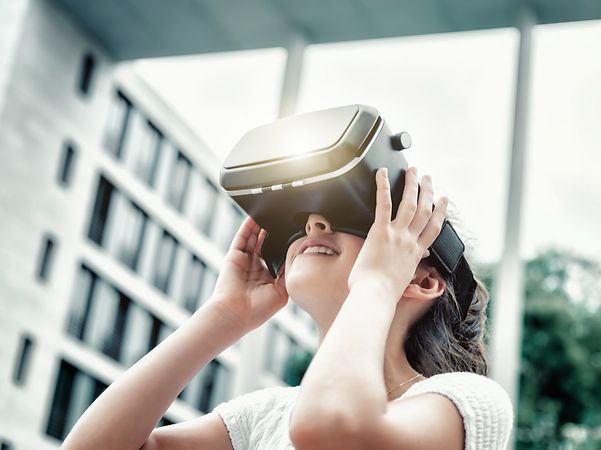 Person steht in einem modernen Raum und nutzt ein Virtual‑Reality‑Headset als Symbol innovativer Lernmethoden