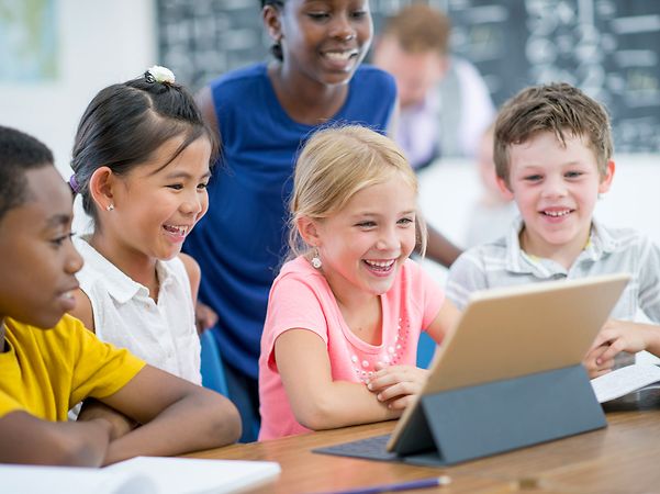Grundschulkinder lernen gemeinsam mit einem Tablet im Klassenzimmer
