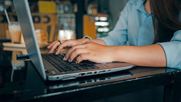 Frau sitzt am Laptop im Büro und nutzt SAP®-ERP von der T-Systems.