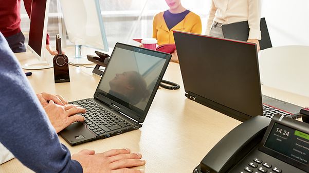 Personen arbeiten an Laptops in einem modernen Büro mit Besprechungstisch