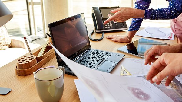 Team arbeitet mit Laptop und Unterlagen an einem Besprechungstisch