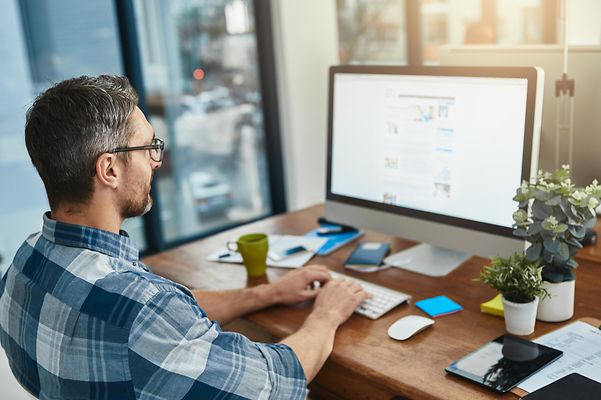 Person sitzt am Schreibtisch am Computer und nutzt Open-Source Collaboration Plattform