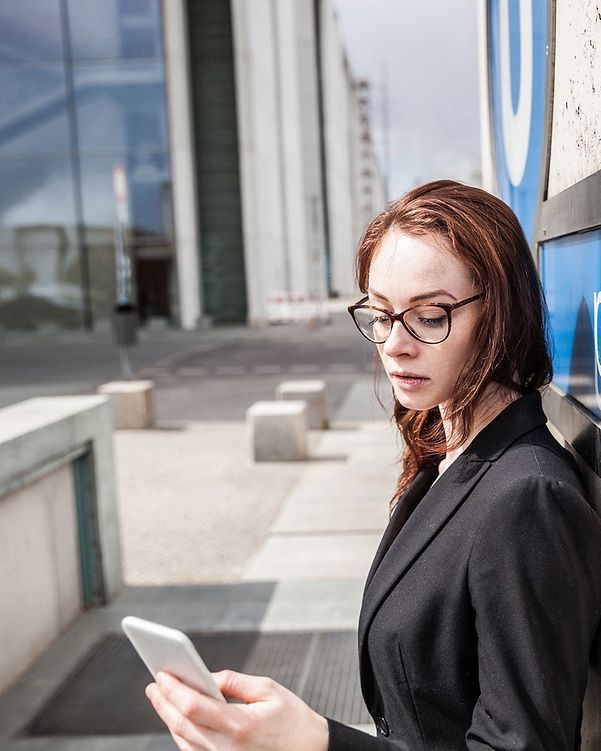 Frau blickt draußen auf ihr Smartphone.