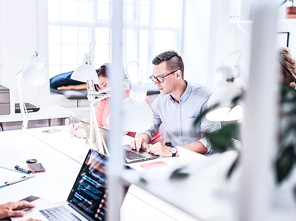 Personen arbeiten gemeinsam an Laptops in einem modernen Büro