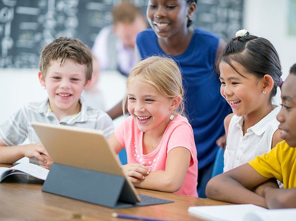 Schüler schauen gemeinsam auf ein ipad und lernen