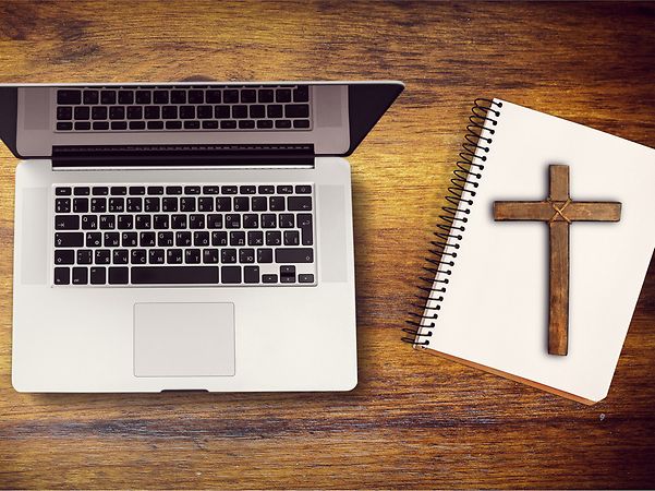 A laptop next to a notebook with a cross symbolises the digitalisation of the Church.