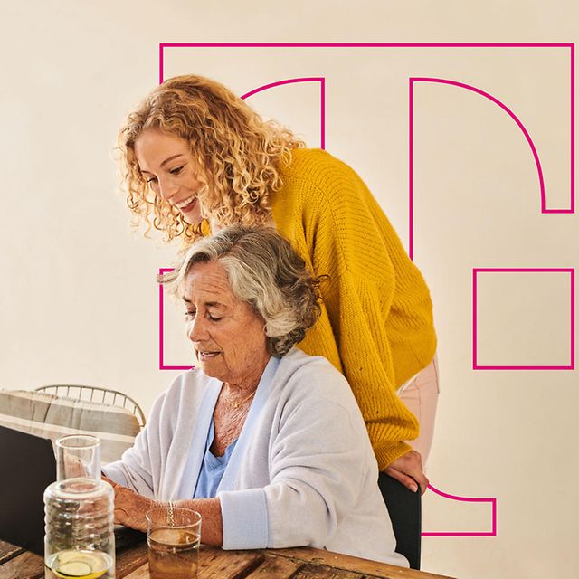 Two people are sitting at a table, sharing a laptop