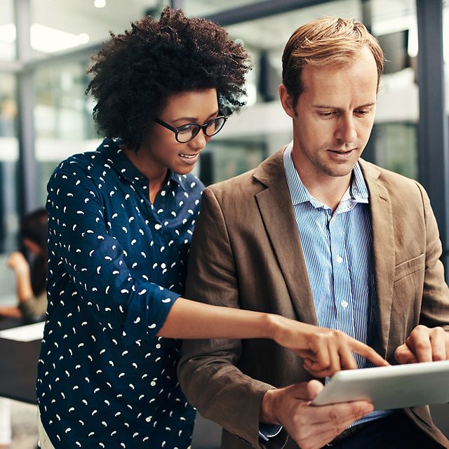 Two people working together on a tablet in a modern office