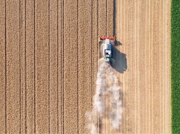Aerial view of a tractor working in a field and kicking up dust.