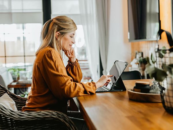 A person is working on a tablet at a table in a modern interior