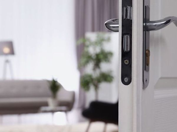 Offene Tür mit Blick in einen hellen Wohnraum mit Sofa und Pflanzen.