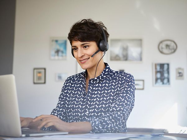 Telekom-Mitarbeiterin berät Kundin oder Kunde via Telefonat am Computer.