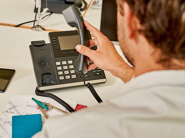 A person is using a landline telephone at their desk.