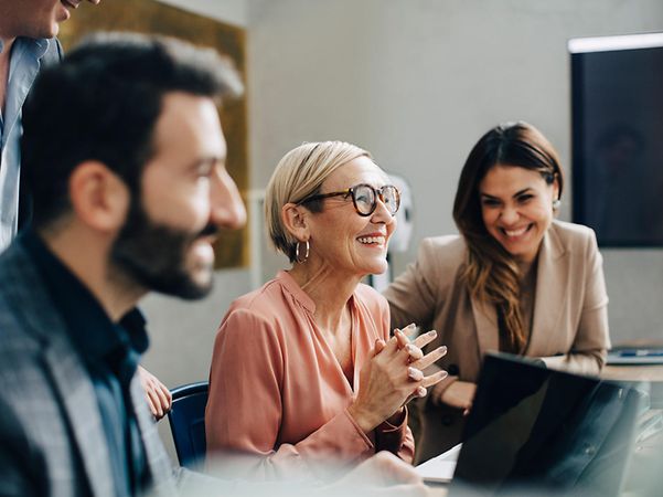 A group of people working together on a laptop in a meeting room