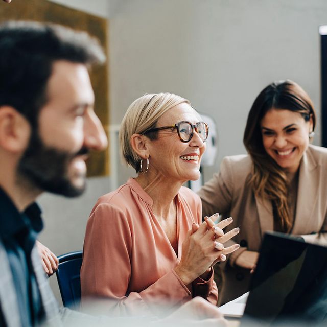 Several people are working together on a laptop during a meeting