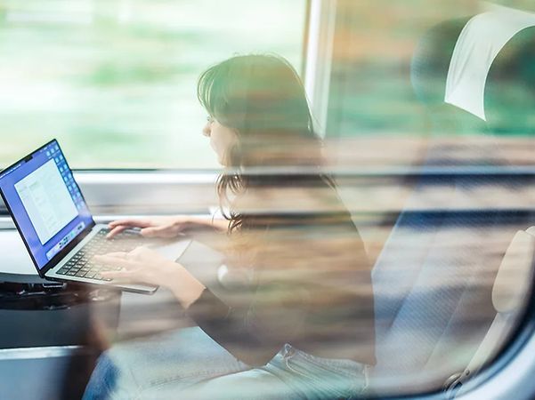 A person is working on a laptop whilst on the move
