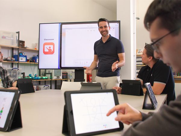 The teacher gives a presentation in the classroom whilst the pupils work on their tablets.