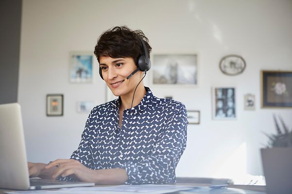 A Telekom employee advises a customer over the phone whilst working at a computer.