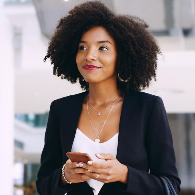 A smiling woman is holding her mobile phone.