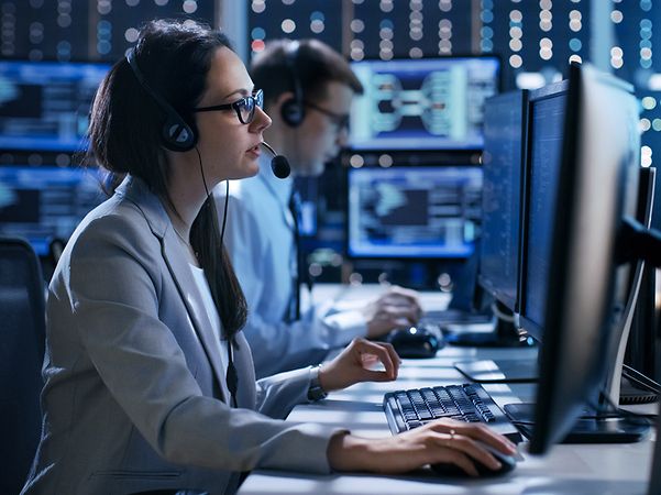 A person is working at several monitors in a control room environment