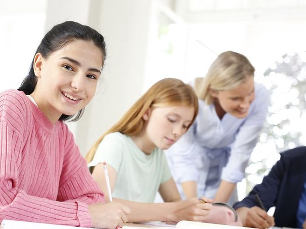 Pupils work together with a teacher at a table.
