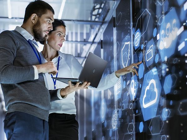 Two people are standing in the data centre, looking at complex services that are invoiced via XRechnung