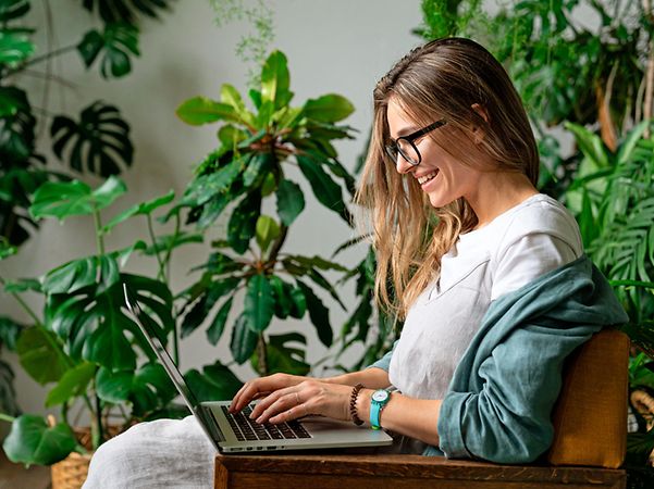 A woman works with a smile, using a laptop and SAP® for administrative digitalisation.