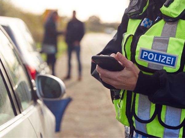 A police officer is using a smartphone during a roadside traffic stop.