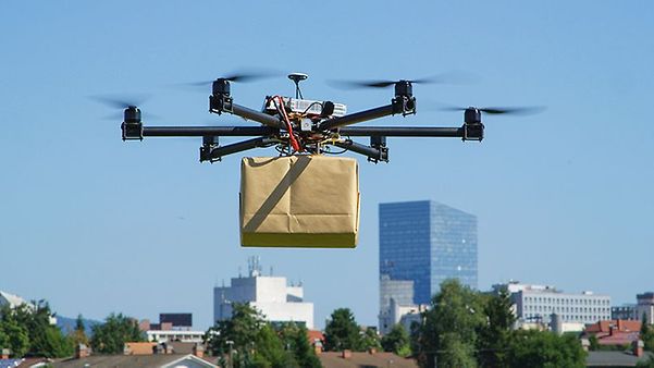 A drone delivers a parcel over an urban landscape