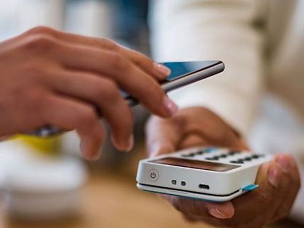 A person makes a contactless payment using a smartphone at a card reader.