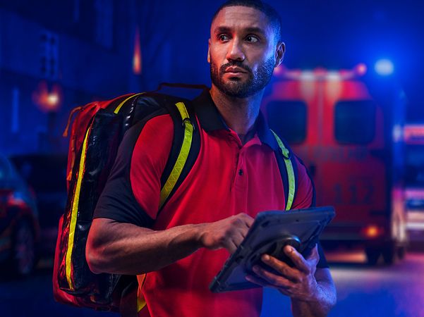 A person in uniform is standing in front of a brightly lit fire engine